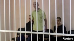 Britons Aiden Aslin and Shaun Pinner and Moroccan Brahim Saadoun appear in a courtroom cage at a location said to be Donetsk.