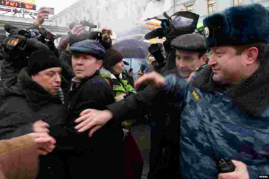 Еще одно задержание показавшегося подозрительным пожилого человека (слева). Оказавшийся рядом известный правозащитник Лев Пономарев возмущается и пытается помешать задержанию, тогда на помощь агенту в штатском приходит сотрудник в форме