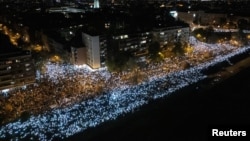 People flash mobile phone lights during 16 minutes of silence on the first anniversary of the fatal Novi Sad railway station canopy collapse.