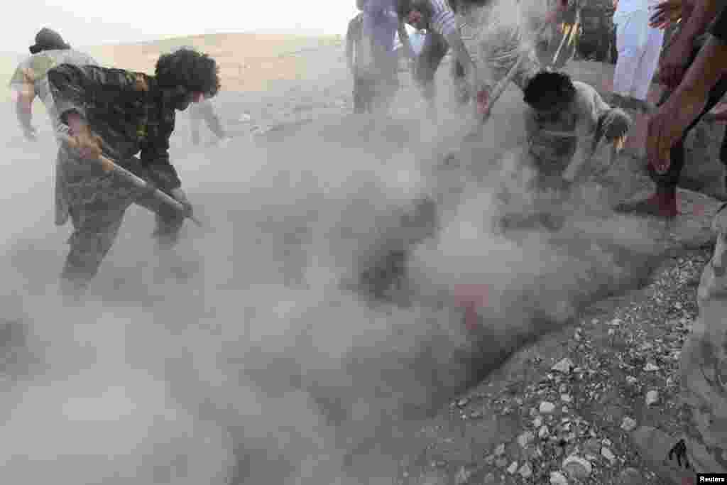 Men bury the bodies of Syrian rebel fighters whom activists said were killed by barrel bombs dropped by forces loyal to President Bashar al-Assad in the Hama region on June 10. (Reuters/Nour Fourat)