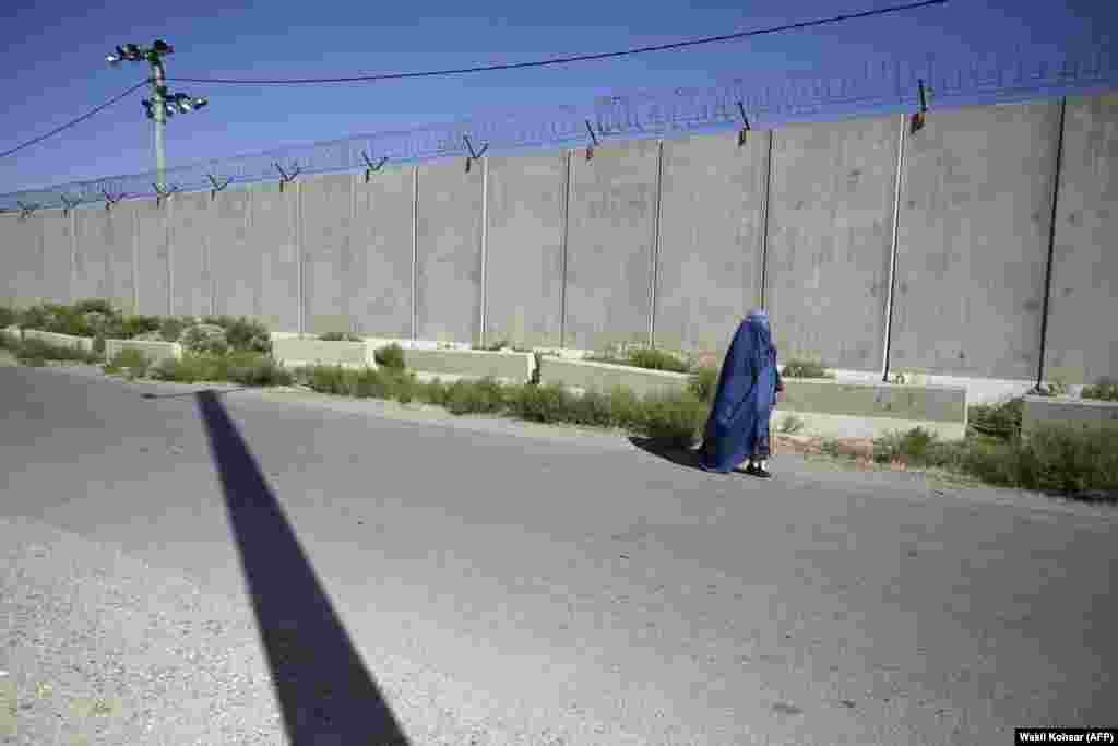 A woman in a burqa walks along a road outside the former U.S. military base in Bagram on July 1. Burqas are full-body coverings with a mesh covering for the face. Some fundamentalist Muslims interpret disputed passages in the Koran as requiring women to entirely cloak themselves when in public.