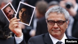 Director Mohammad Rasoulof holds pictures of cast members Missagh Zareh (left) and Soheila Golestani following the screening of his film The Seed Of The Sacred Fig in Cannes. 