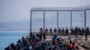 Bevándorlók várnak, hogy bejuthassanak a Marokkó és Spanyolország határához közeli Ceuta spanyol enklávéba, 2021. május 18-án.