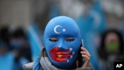Protestatar uigur care trăiește în Turcia, purtând o mască cu un steag chinezesc