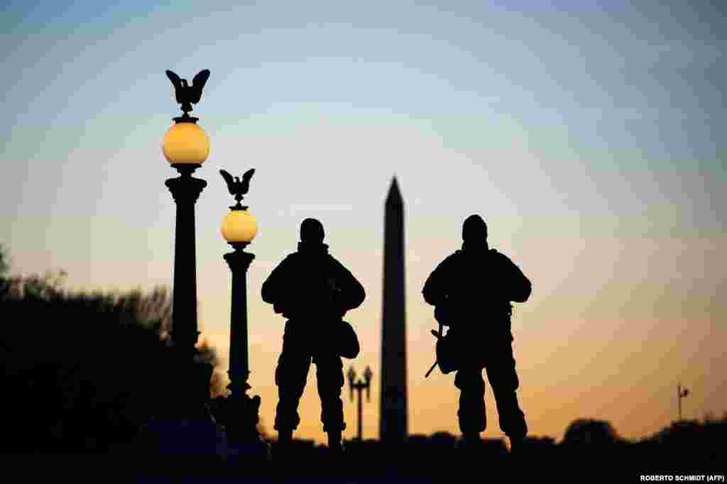Siluete pripadnika Nacionalne garde dok čuvaju stražu ispred zgrade Capitola i blizu spomenika Washingtonu u Washingtonu, 19. januara, uoči ceremonije inauguracije. &nbsp;