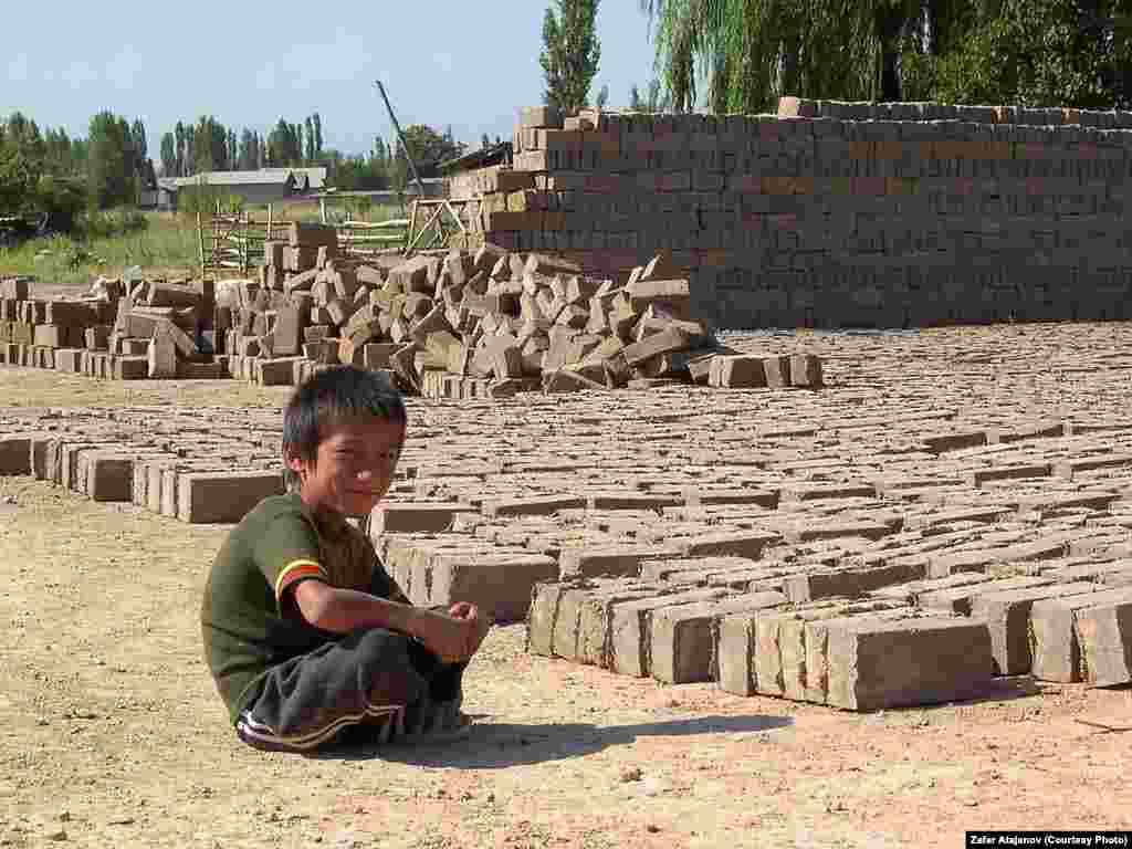 A Kyrgyz child takes a break from making clay bricks to sell.