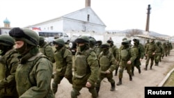 Armed men, believed to be Russian servicemen, walk outside a Ukrainian military base in Perevalnoye, near the Crimean city of Simferopol on March 14.