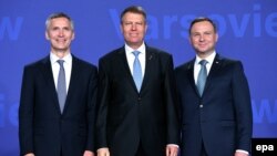 Președintele polonez Andrzej Duda dr.) și secretarul-general NATO, Jens Stoltenberg, salută sosirea președintelui român la summitul de la Varșovia la 8 iulie