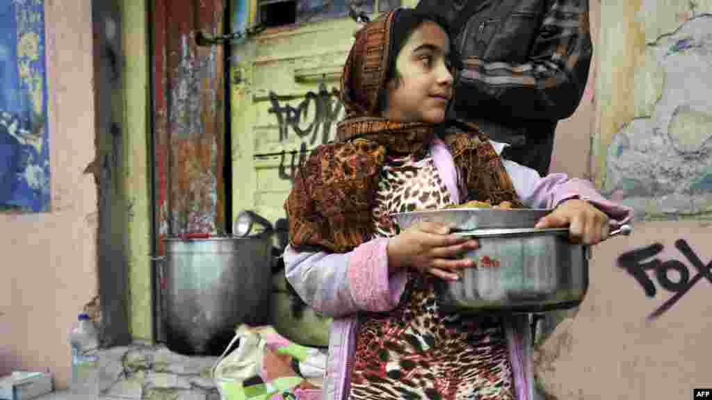 Fatima, an Afghan immigrant, carries food donated by activists from a soup kitchen in a poor neighborhood in Athens, Greece.