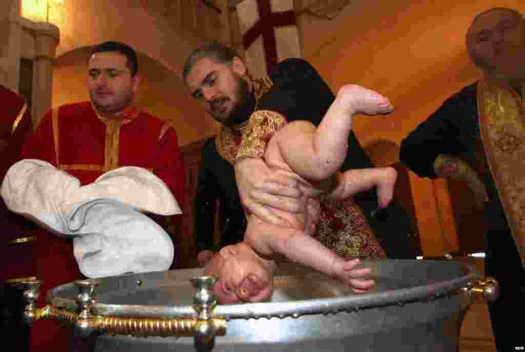 An Orthodox priest baptizes an infant during a mass baptism of some 900 babies into the Georgian Orthodox Church in Tbilisi. (EPA/Zurab Kurtsikidze)