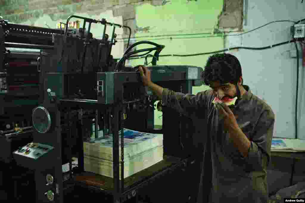 A newspaper printer snacks on a slice of watermelon on a summer night in Kabul.