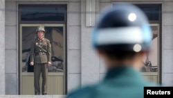 Солдат армии КНДР (слева) и южнокорейский солдат несут службу по охране границы у разделительной линии между двумя странами