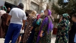 People wait in line for subsidized food at a state grocery in the Lebap region.