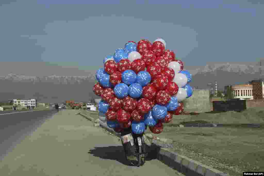 An Afghan balloon vendor riding his bicycle looks for customers in Kabul. (AP/Rahmat Gul)