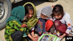 چهار تن از اطفال در حال تماشای یک پوستر مربوط به خطرات مواد منفجر ناشده در افغانستان