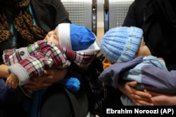 Two babies are held by their mothers, as one of them breast feeds, at the Mofid Children's Hospital in Tehran. (file photo)