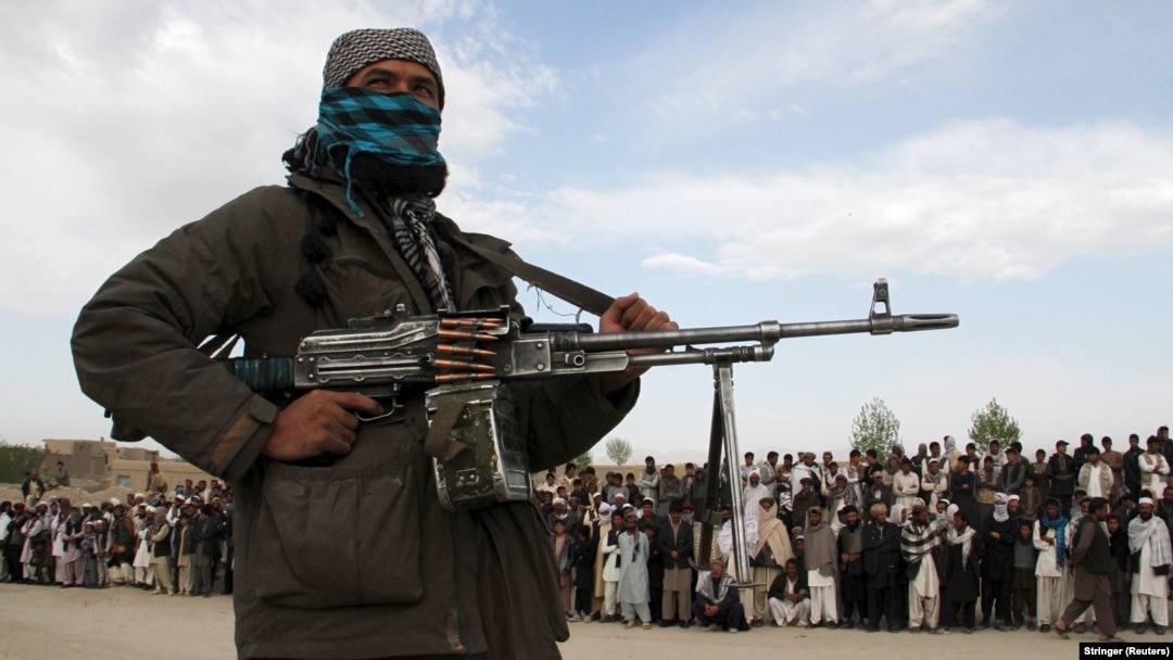 A member of the Taliban and bystanders witness the execution of three men in Ghazni Province. (file photo)
