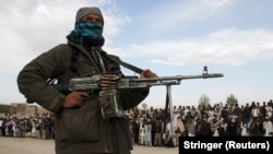 A Taliban fighter and onlookers witness the execution of three men in Ghazni Province in 2015.