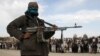 A Taliban fighter and onlookers attend the execution of three men in Ghazni Province in April 2015.