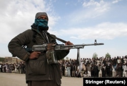 Вооруженный боевик и толпа зевак на месте казни трех мужчин в провинции Газни в 2015 году