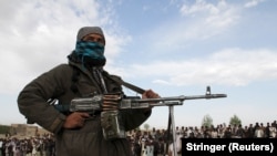 Një luftëtar taliban dhe shikuesit marrin pjesë në ekzekutimin e tre burrave në provincën Ghazi në Afganistan, prill 2015.