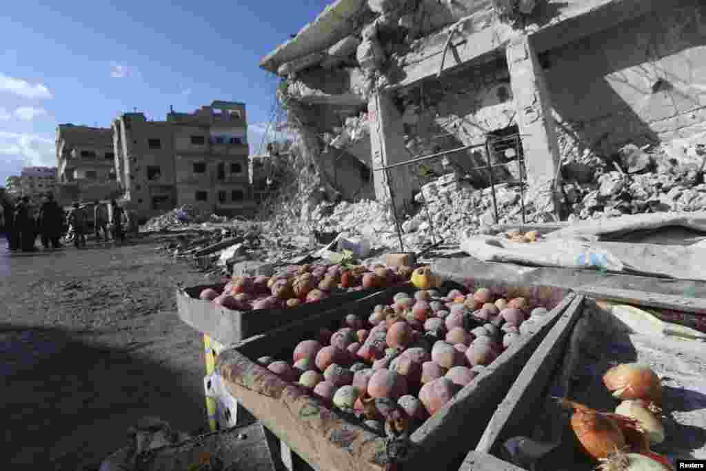 Vegetables are covered in dust as people inspect a site hit by what activists said were air strikes carried out by the Russian Air Force on a busy market in the town of Ariha, in Idlib Province, Syria. (Reuters/Ammar Abdullah)