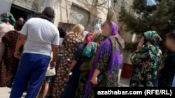 People wait in line for subsidized food at a state grocery in the Lebap region.