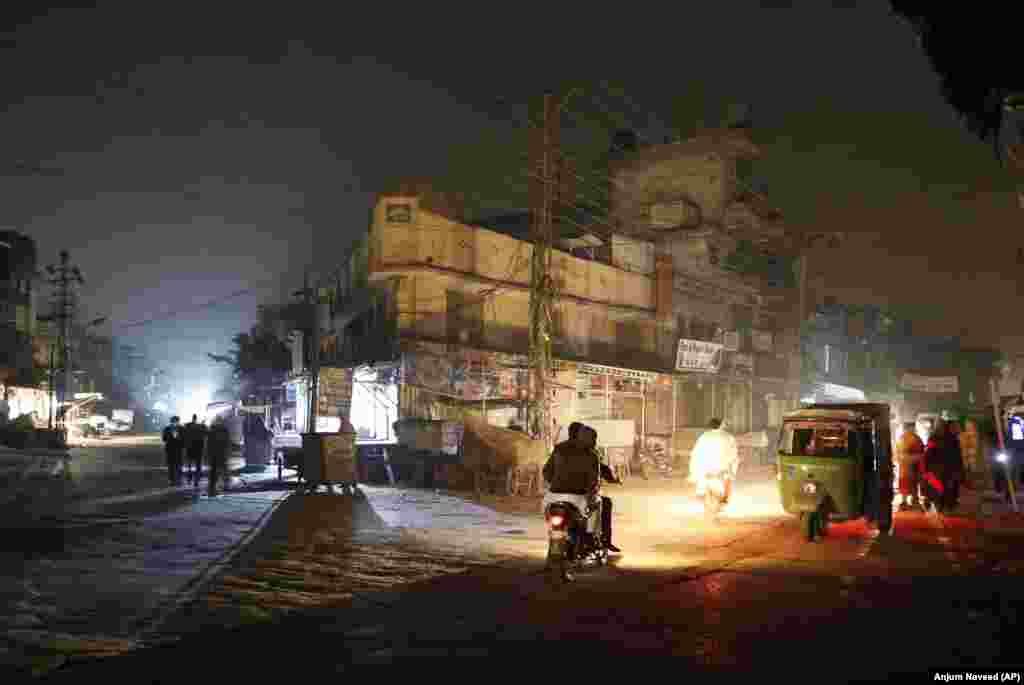 Улица, освещенная фарами автотранспорта, во время массового отключения электроэнергии в Равалпинди, Пакистан. В национальной энергосистеме Пакистана произошел серьезный сбой, в результате чего миллионы людей остались в темноте. (AP/Анджум Навид)