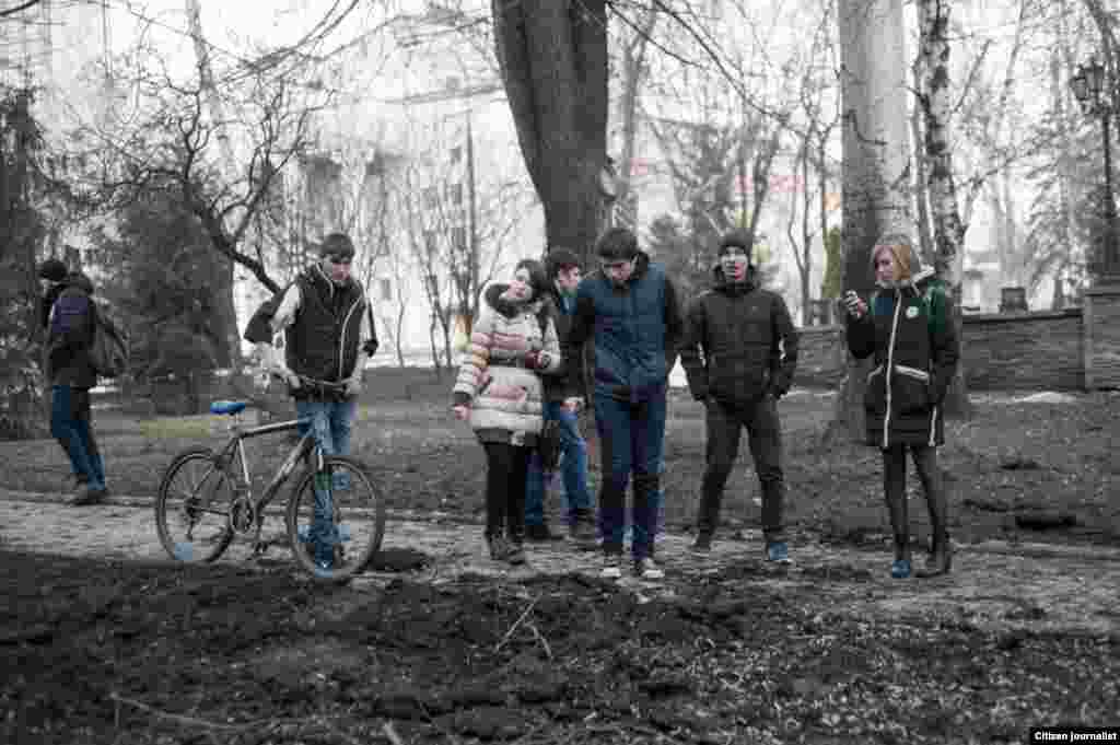 Donetsk, Ukrain. Several artillery shells hit the very city centre, which has never happened before. It is the last day befor ceasefire. Passer-by standnear explosion crater.