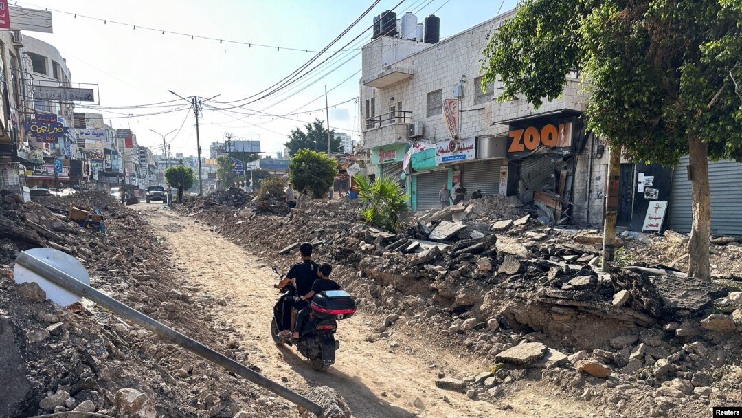 Un palestinian conduce o motocicletă pe o stradă puternic avariată în urma operațiunii militare israeliene în Jenin. 6 septembrie 2024.