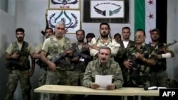 Free Syrian Army chief Riad al-Asaad (center) reading a statement from an undisclosed location in Syria in September 2012. (screen shot)