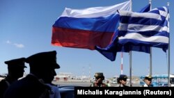 Сотрудники полиции и военные на фоне флагов Греции, России и Европейского союза. Иллюстративное фото.