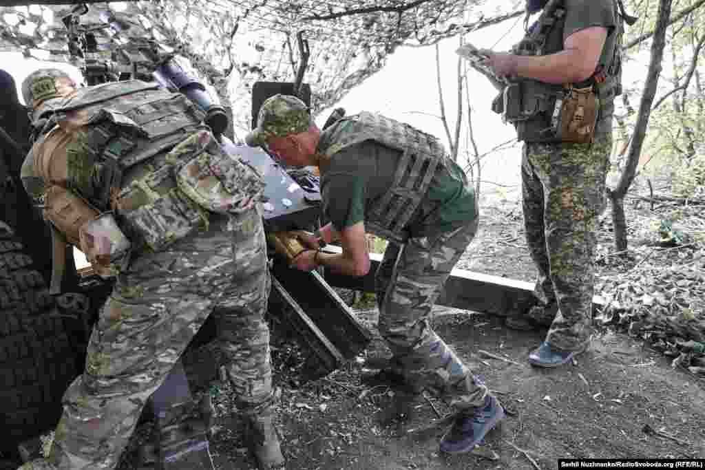 Dmytro loads the shell into the chamber and closes the breech, preparing it for the next salvo.