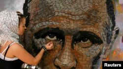 Ukrainian artist Daria Marchenko works on a portrait of Russian President Vladimir Putin that is made out of 5,000 cartridges brought from the frontline in eastern Ukraine.