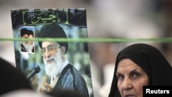 A woman holds a picture of Supreme Leader Ayatollah Ali Khamenei while attending Friday Prayers at Tehran University, which hosted the National Soft War Forum.