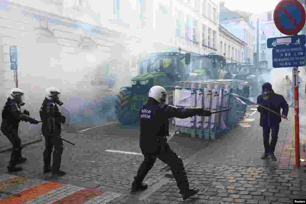 Un ofițer de poliție încearcă să oprească un protestatar care vrea să treacă peste filtrul forțelor de ordine.