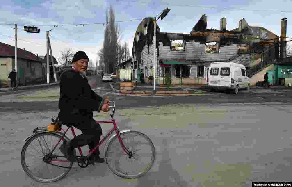 An elderly man cycles past a burnt out building in the majority-Dungan village of Masanchi - in southern Kazakhstan&#39;s Jambyl region close to the border with Kyrgyzstan - on February 12, 2020.&nbsp;