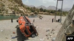 Onlookers stand next to a damaged bus at the site of an accident in a remote district of Balochistan Province. (file photo)