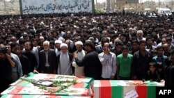 A cleric prays over the coffins of the bombing victims during a mass funeral in Zahedan.