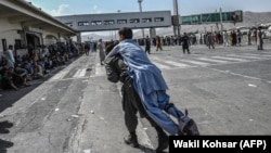 Кабул әуежайында ер адам жараланған адамды арқасына көтеріп барады. 16 тамыз 2021 жыл.