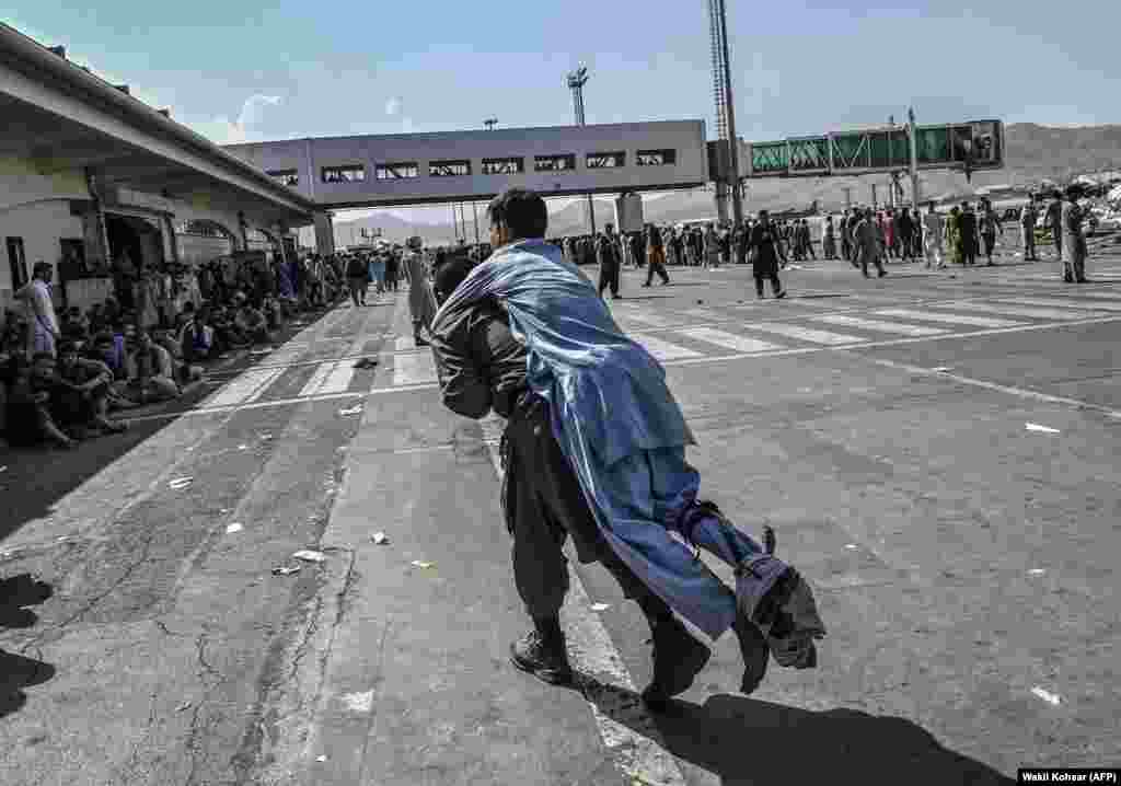 An injured man is carried among the crowds at the airport.&nbsp;