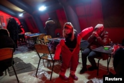 People warm themselves in an emergency shelter tent in Kyiv on January 13.