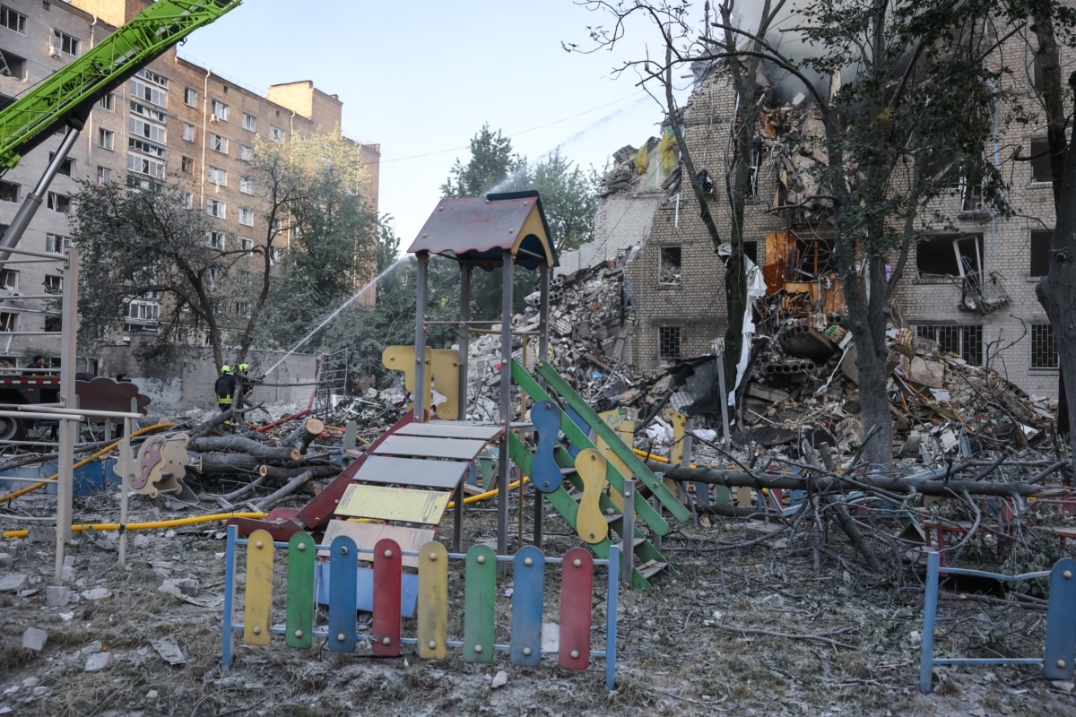 Пошкоджений дитячий майданчик поруч зі зруйнованою багатоповерхівкою