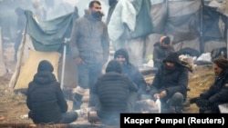 Migrants gather around a fire in a camp in the Hrodno region of Belarus on November 18.