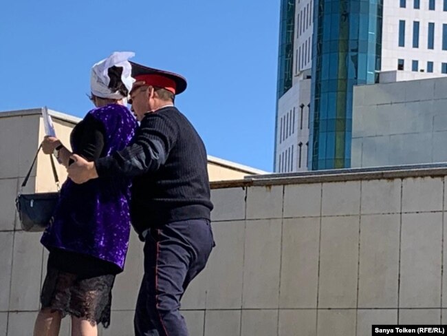 Полиция қызметкері Қанағат Тәкееваны президент әкімшілігі кеңсесіне қарай жетектеп барады. Нұр-Сұлтан, 20 қыркүйек 2019 жыл.