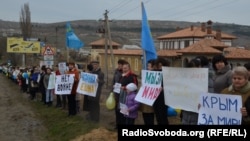 Кримчанки з кримськотатарськими прапорами та плакатами за мир стоять біля однієї з кримських автотрас. Крим, 08 березня 2014 року