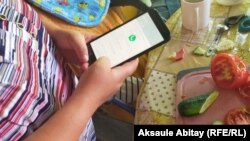 Мүмкіндігі шектеулі Оксана айтпақ болғанын смартфонға жазып, өзгелермен сөйлеседі. Тараз, 20 маусым 2020 жыл.