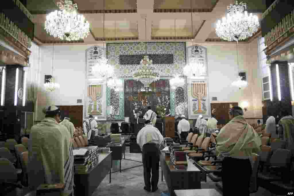 Iranian Jewish men wearing Tallit shawls read from the Torah during morning prayers.