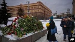 People lay flowers to pay last respects to Aleksei Navalny at the Solovetsky Stone, a monument to political repression, in Moscow on February 17. 