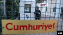 An armed private security officer stands guard in front of the headquarters of the Cumhuriyet daily newspaper in Istanbul.